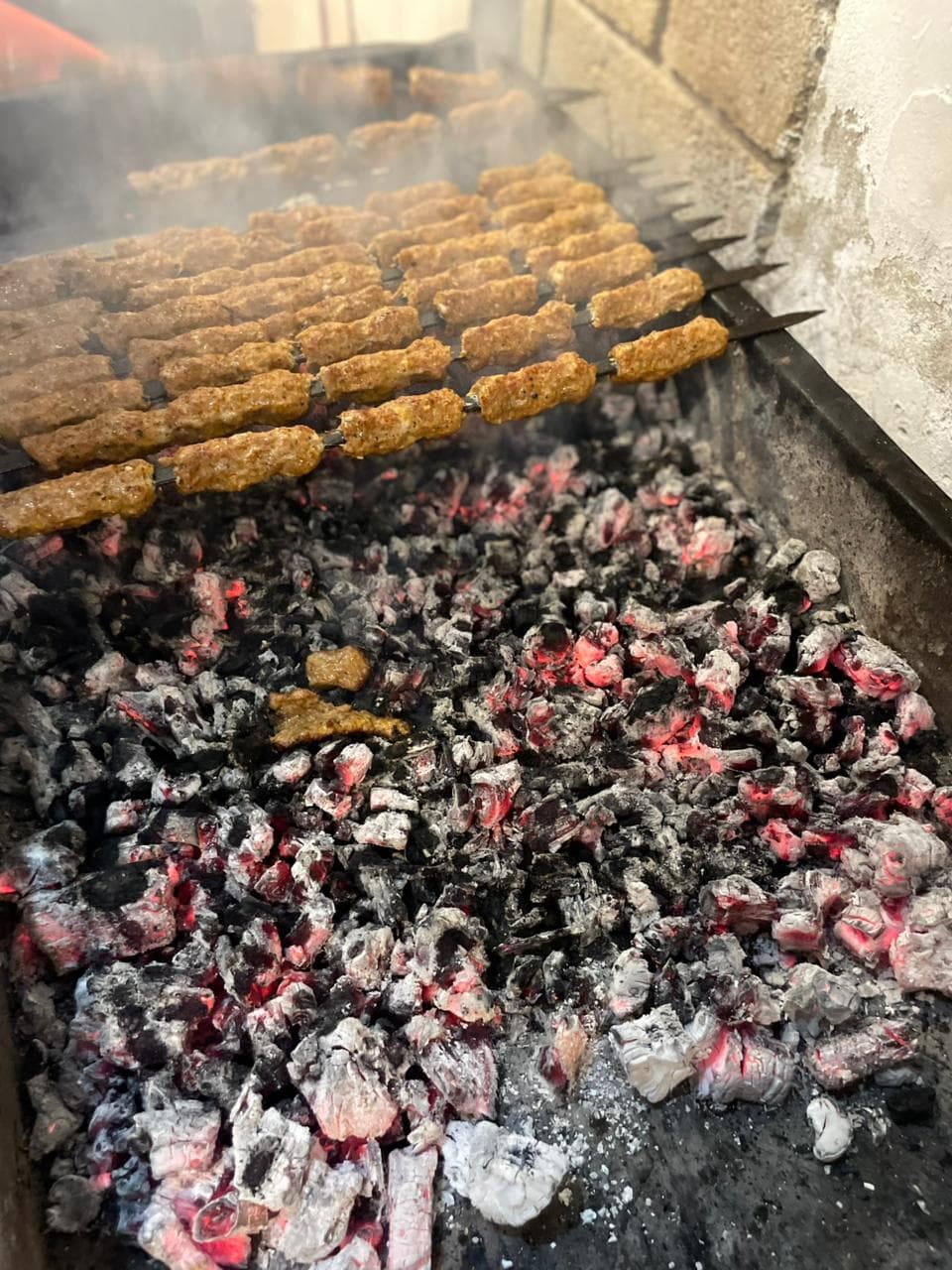 A grill loaded with kebabs being cooked over hot coals.