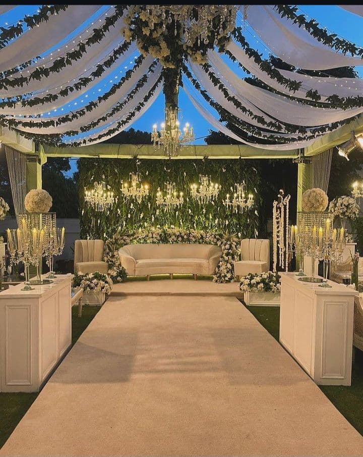 A wedding reception featuring elegant white and green decor, with tables set for guests and floral arrangements.
