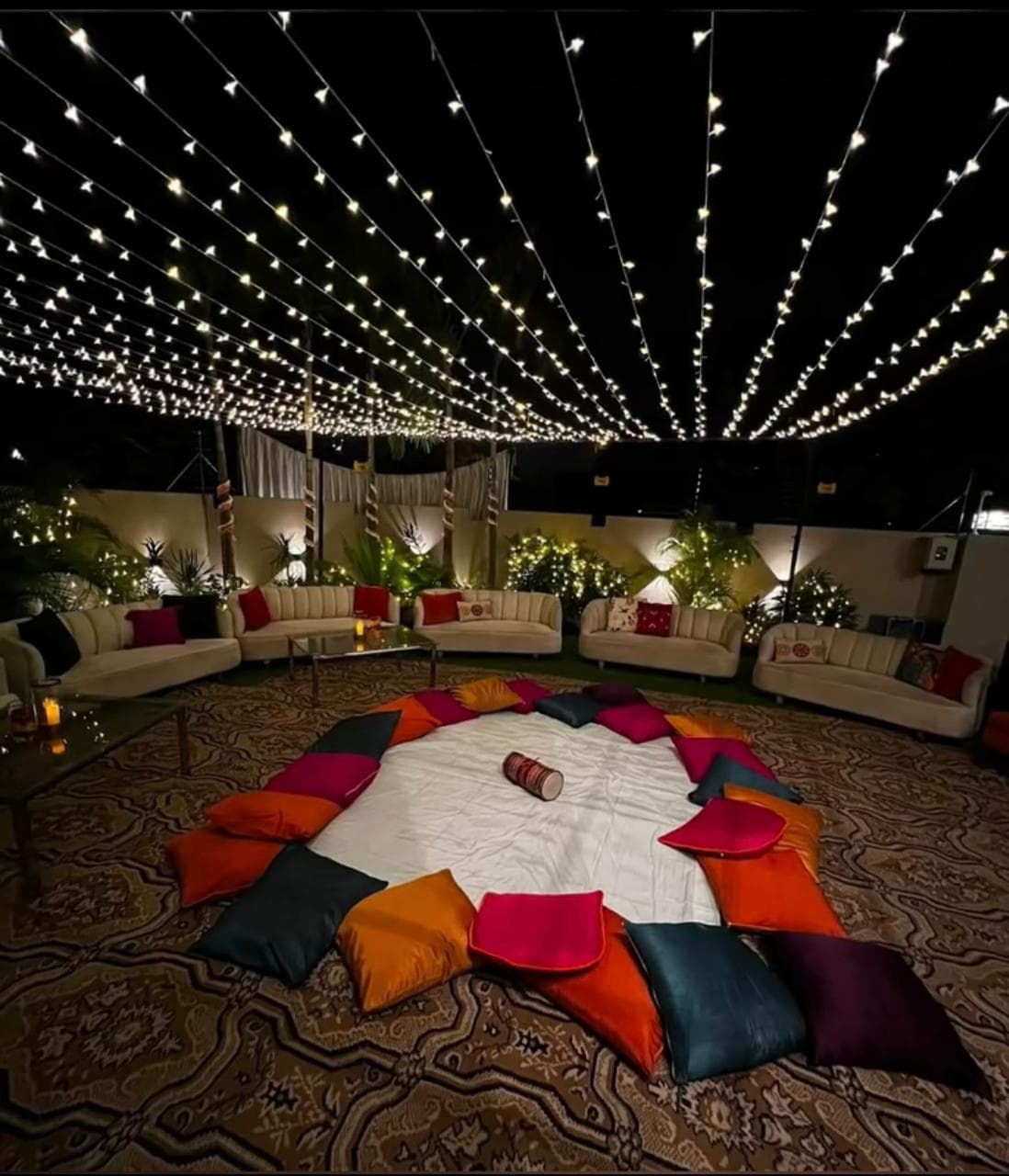A spacious room filled with vibrant pillows and decorative lights, creating a cozy and inviting atmosphere.