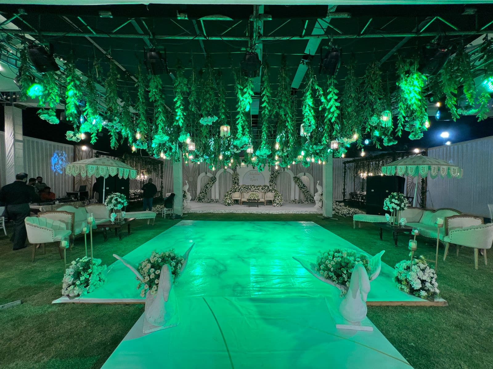A beautifully decorated wedding reception featuring green lights and vibrant flowers, enhancing the celebratory mood.