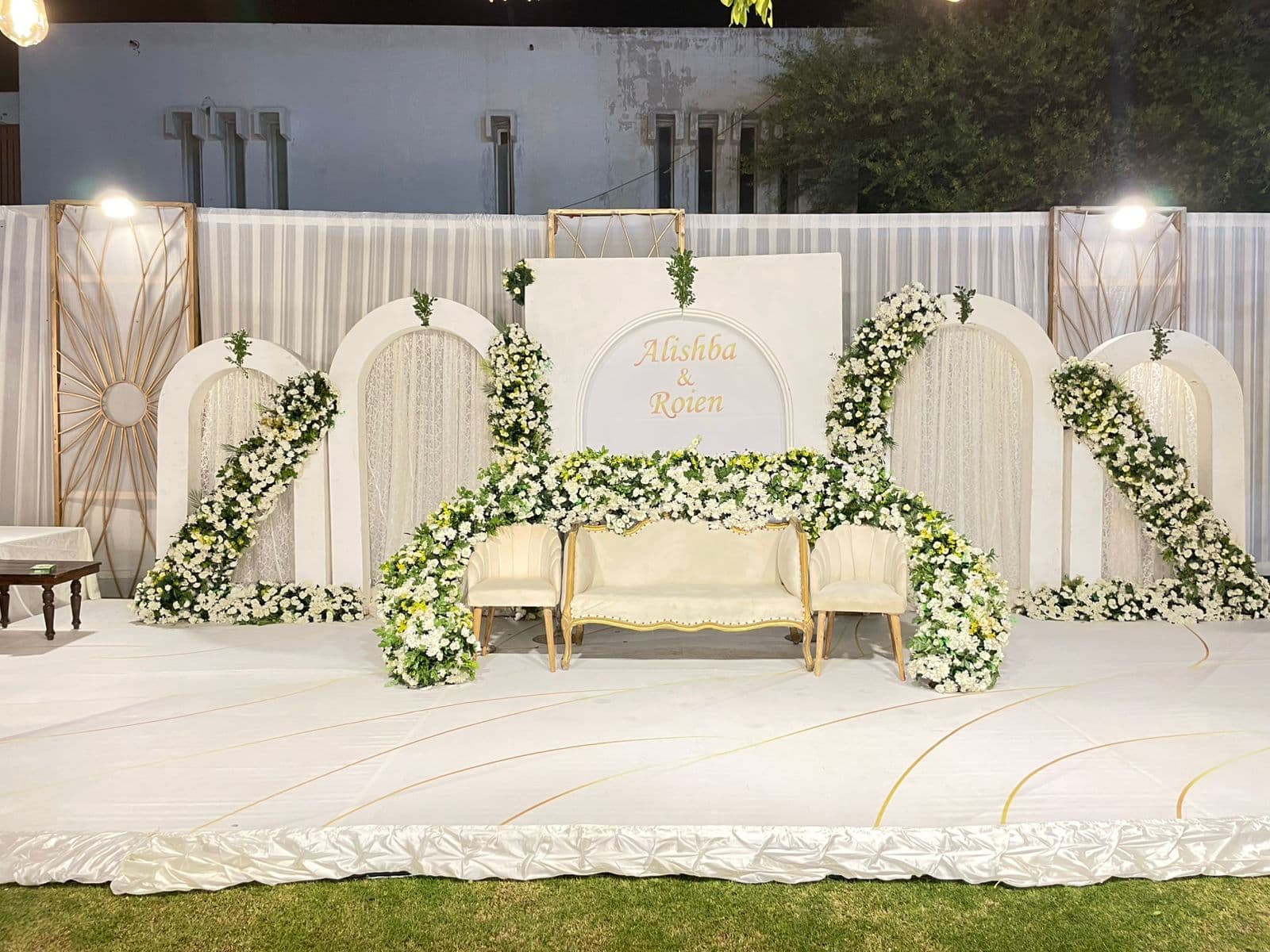 An exquisite wedding stage showcasing white flowers and gold decor, setting a charming backdrop for the ceremony.