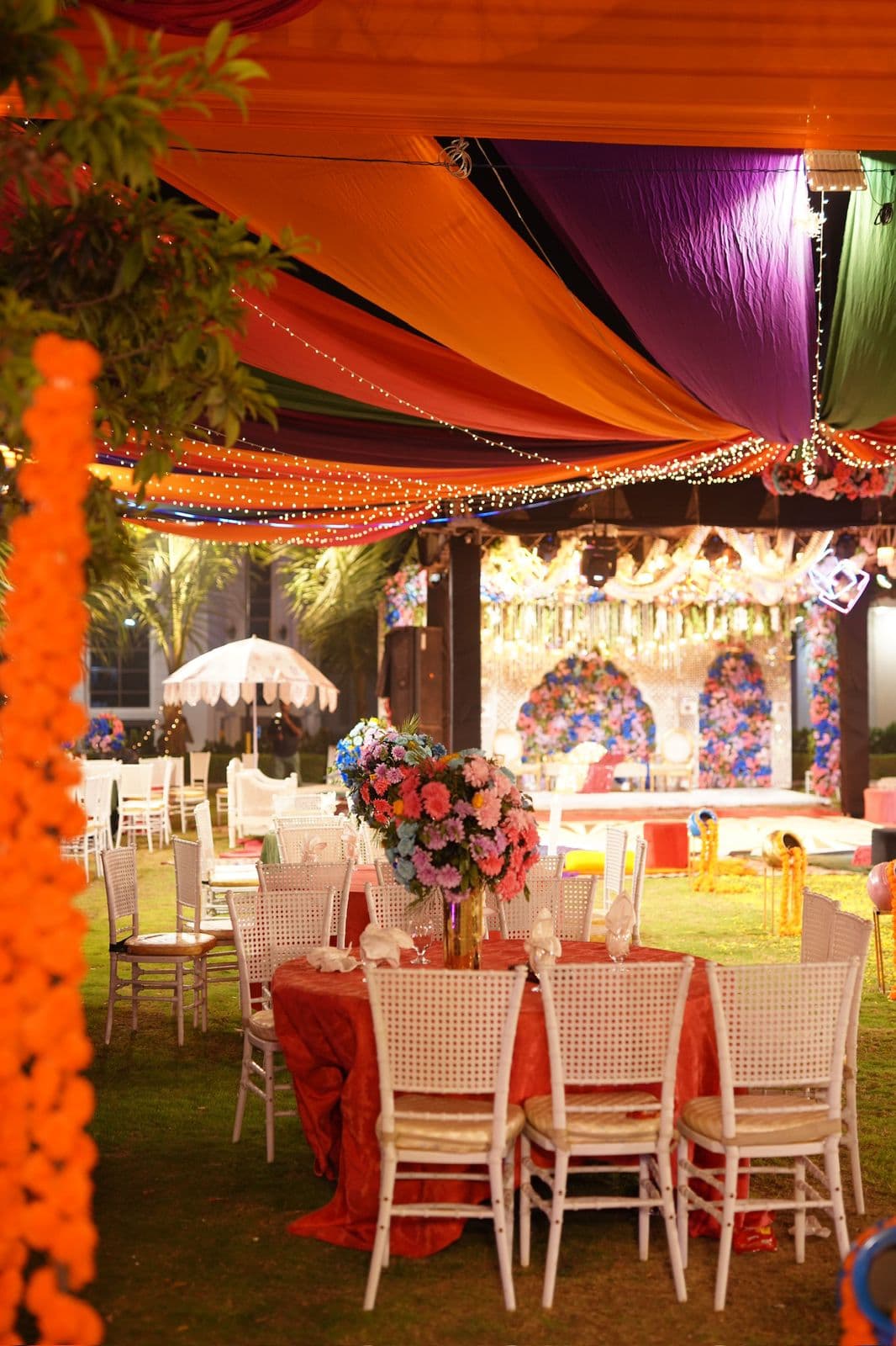 An outdoor wedding reception scene showcasing bright tables and chairs set up for guests amidst a picturesque landscape.