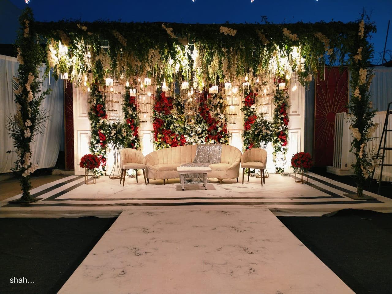 A beautifully decorated outdoor wedding stage featuring an array of colorful flowers and greenery, set for a joyful celebration.