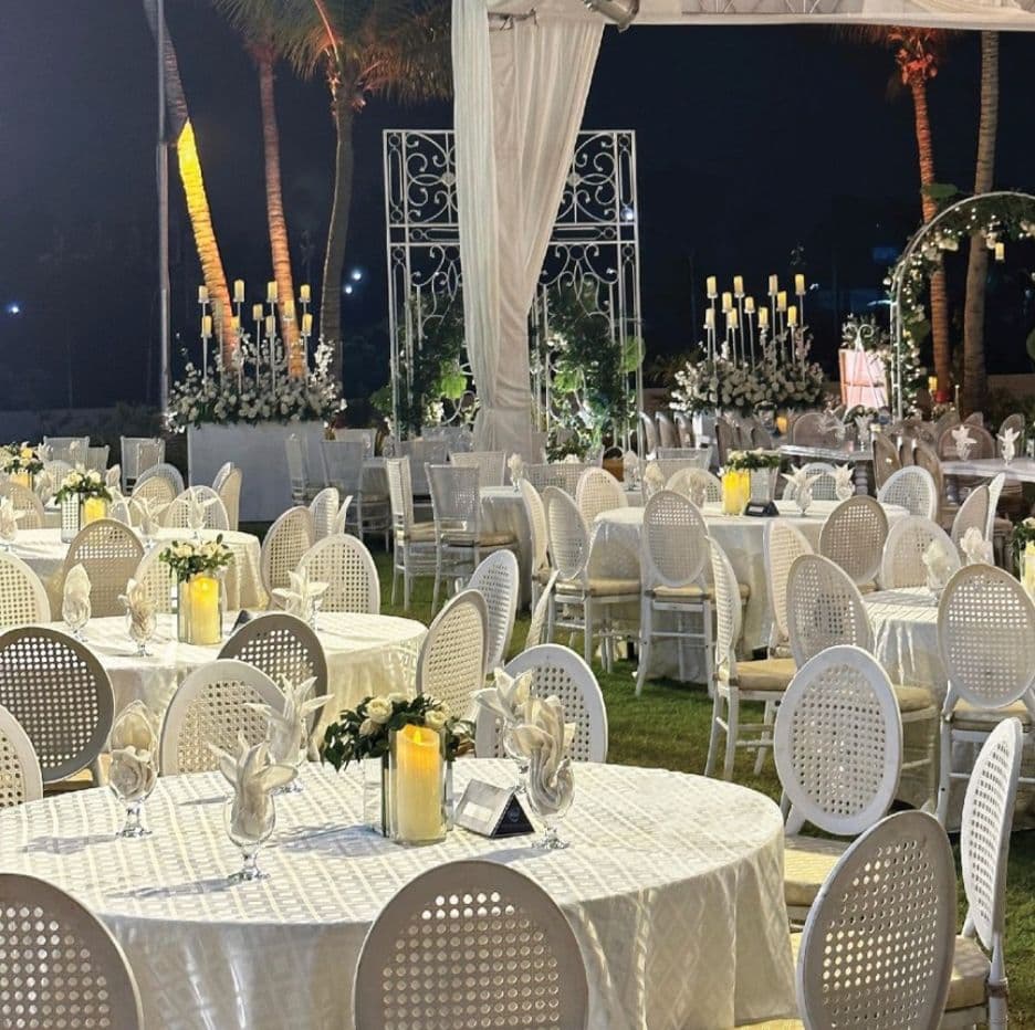 A wedding reception featuring elegantly arranged white chairs and tables set for guests.