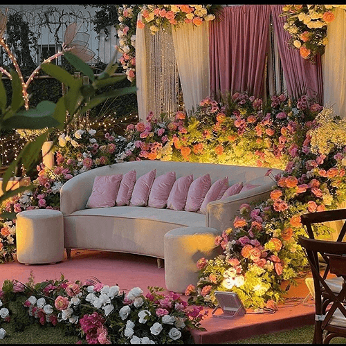An ornate wedding stage with floral decorations and a plush couch, designed for a memorable wedding event.